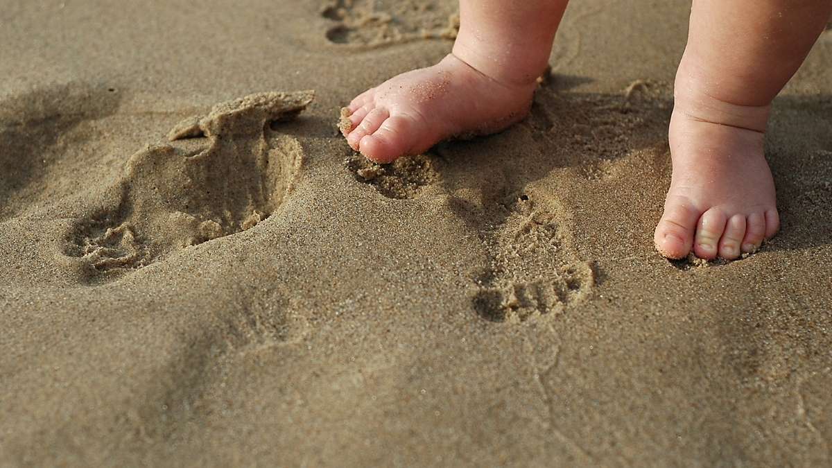 marcas dos pés do bebê na areia